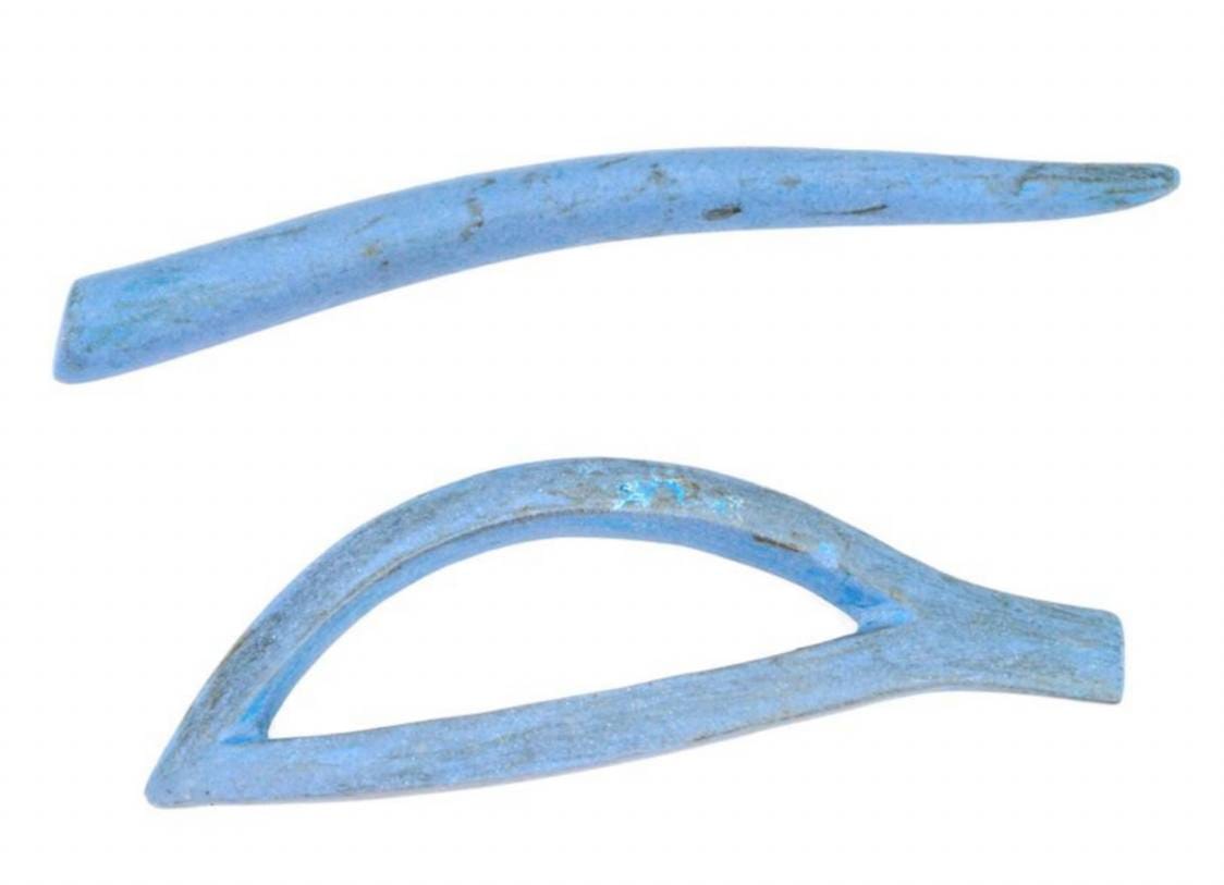 Deux pièces bleues usées sur fond blanc : une bande courbe en forme de sourcil au-dessus et un contour d'œil en amande ajouré en dessous.
