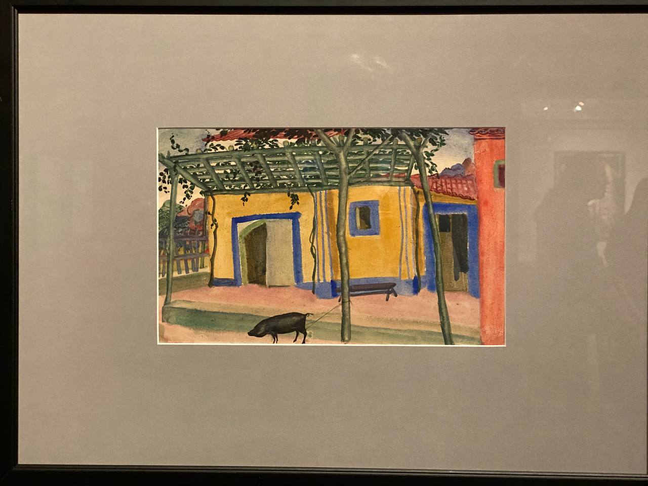 Aquarelle encadrée : maison jaune aux encadrements bleus, pergola en treillis vert, pilier rouge à droite. Au premier plan, un cochon noir tenu par une corde.