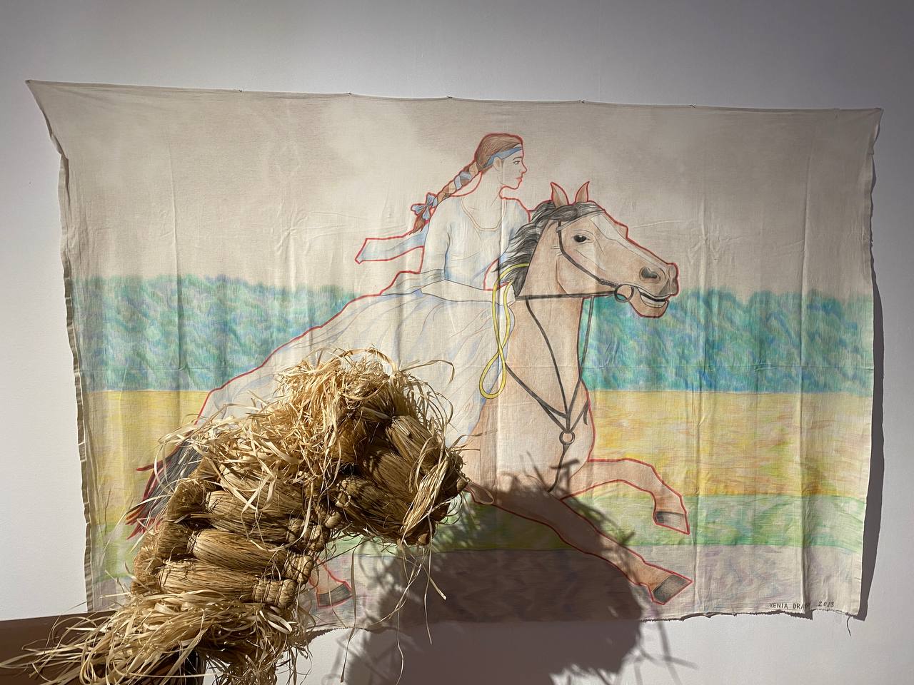 Dessin au crayon de couleur sur toile : une jeune femme tressée, en robe blanche, galope à cheval. Au premier plan, une sculpture en paille tressée.
