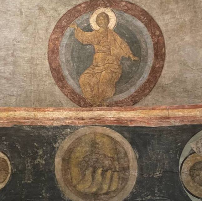 Fragment of an old fresco showing Christ in a round medallion, with a second medallion below containing a faint image.