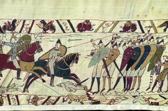 Detail of the Bayeux Tapestry showing mounted warriors attacking foot soldiers with shields, with fallen men below.