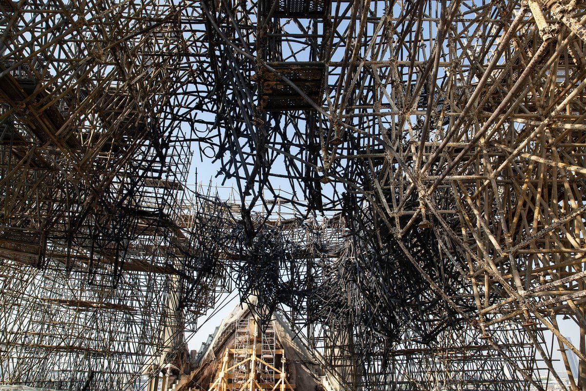 A dense tangle of metal structures, some of them blackened, against a blue sky.