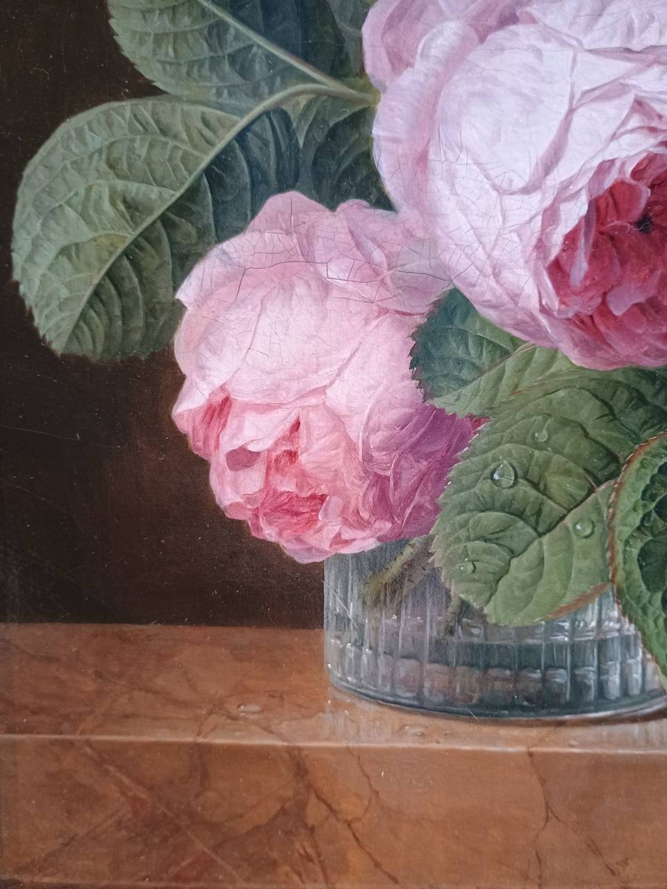 Détail d'un tableau : deux roses roses et des feuilles vertes avec des gouttes de rosée dans un vase en verre sur une tablette de marbre.
