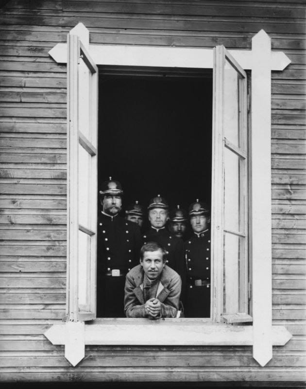 Yegor Larichkin, accused in the case of the murder of Mikhail Gertsenshtein, together with his guards at a window of the building where the court sessions were held