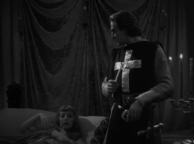 Un homme en cotte de mailles et tunique sombre à croix blanche se tient près d'un lit, un petit objet à la main. Une femme est allongée ; draperies et bougies au fond.