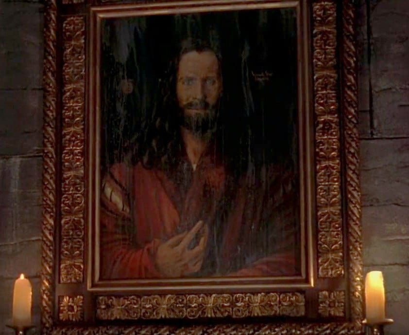 Image du film montrant le portrait d'un homme barbu aux cheveux longs, vêtu de rouge, dans un cadre doré orné, entre deux bougies allumées.