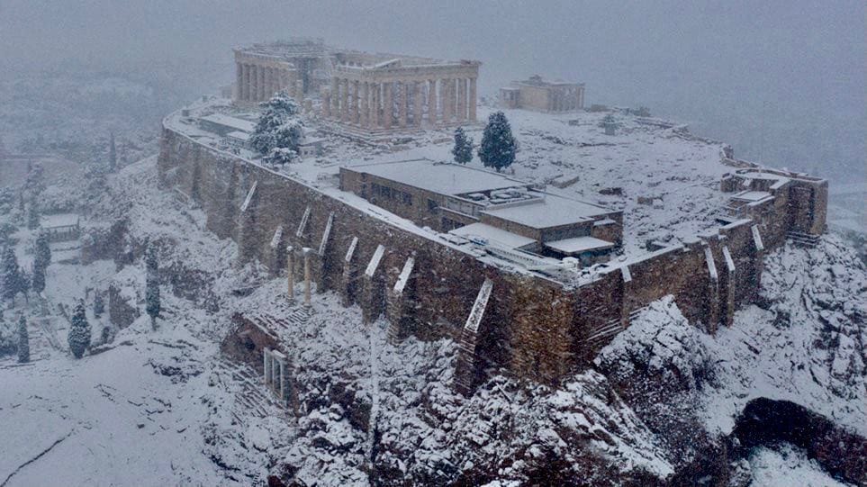 Aerial view of the snow-covered Acropolis with the Parthenon on top of the hill during a snowfall.