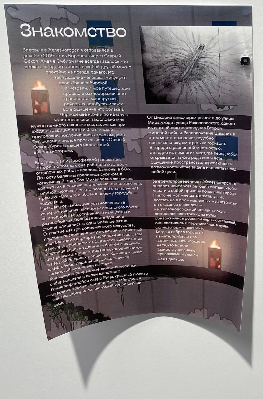 Affiche imprimée sur un mur blanc intitulée « Знакомство » (Rencontre), avec un long texte, un dessin d’insecte à nombreuses pattes et des bougies en pixel art.