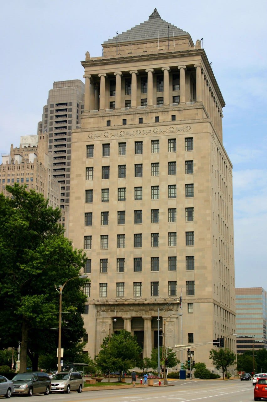Haut édifice en pierre claire, doté d'une colonnade au sommet et d'un toit pyramidal à gradins. L'inscription « Civil Courts » orne l'entrée; au premier plan, arbres, rue et voitures.