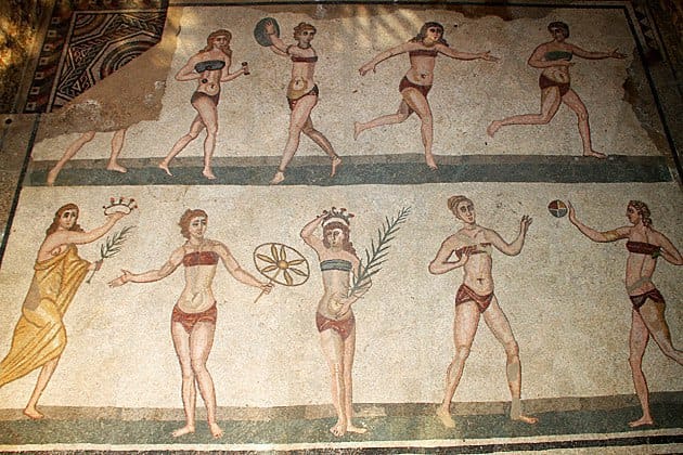 Mosaic of young women in two-piece outfits: above they run and hold a disc and weights, below they play with a ball and hold palm branches and a crown.