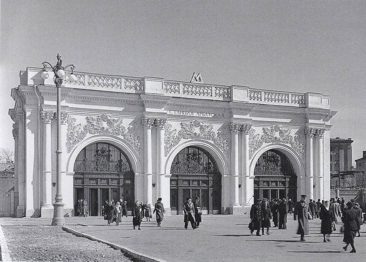 White pavilion of Moscow's Arbatskaya metro station with three arched entrances and stucco decoration, pedestrians in front, photographed in 1953.