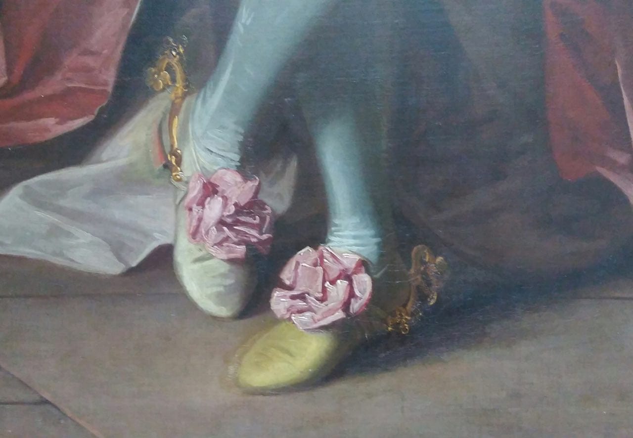 Painting detail: legs in pale blue stockings, one green and one yellow shoe, each with a pink rosette and a gilded spur.