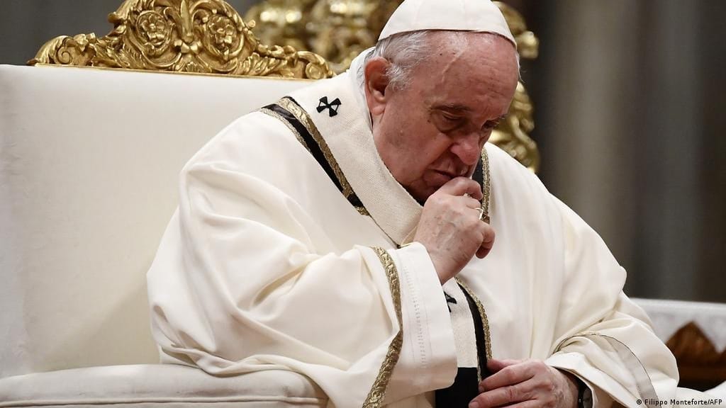 Un homme âgé, coiffé d'une calotte blanche et vêtu d'habits blancs bordés d'or, est assis dans un fauteuil doré, pensif, le poing contre le menton.