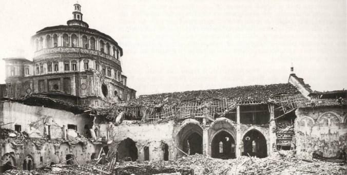 Photo en noir et blanc : un grand dôme à galerie domine un bâtiment endommagé au toit effondré, aux arcades ouvertes, avec des tas de gravats au premier plan.