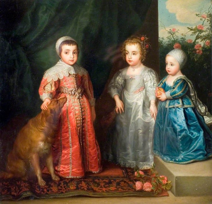 Three small children in satin outfits of red, silver and blue stand on a carpet beside a golden-brown dog.