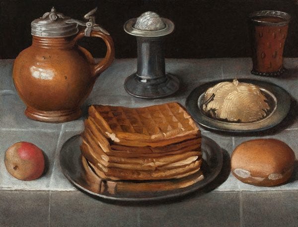 Still life with a lidded clay jug, a pewter plate of stacked waffles, a plate of butter, an apple, a bread roll and a glass on a stone table.