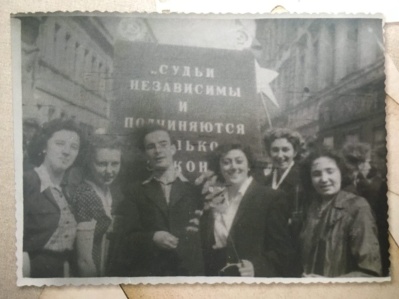 Old black-and-white photograph of five women and a man standing in a street before a poster reading “Judges are independent and subject only to the law”.