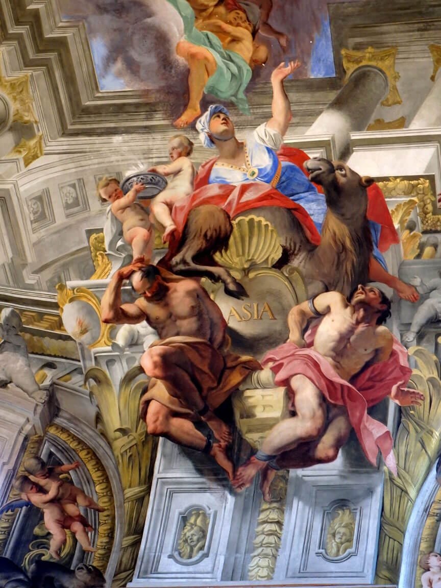 Une femme en turban, vêtue de rouge et de bleu, est assise sur un chameau, le bras levé. Des putti et deux hommes à demi nus l'entourent ; le mot ASIA est inscrit en doré.