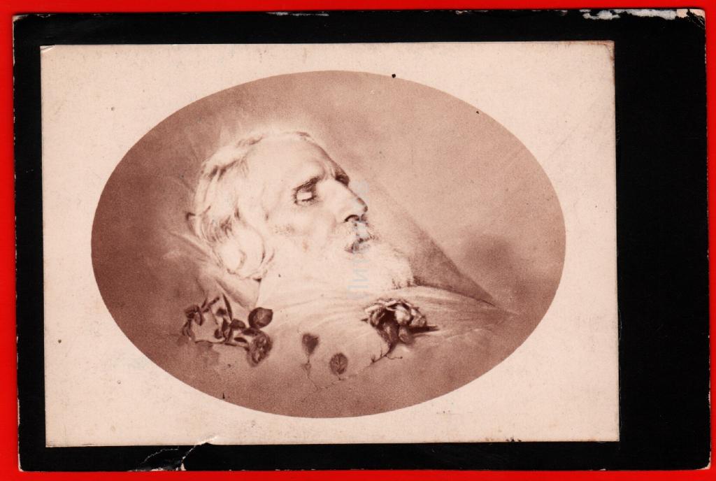 Post-mortem photograph of an elderly man with white hair and beard in an oval frame on a mourning card with a black border.