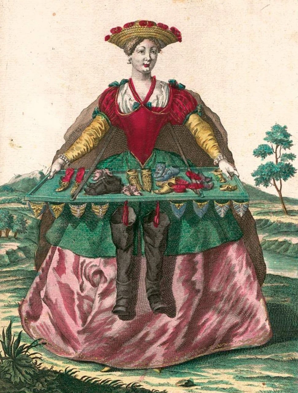 Hand-coloured print of a woman in a flower-trimmed straw hat holding a strapped tray of sample shoes, with boots hanging from her skirt.
