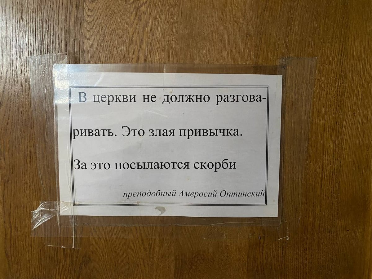 Лист с цитатой преподобного Амвросия Оптинского о разговорах в церкви, приклеенный скотчем к деревянной двери.