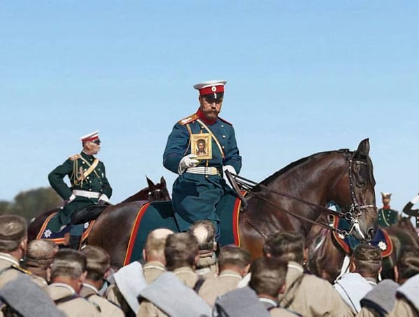 Николай II верхом на коне держит икону перед рядами солдат, рядом на лошади офицер в зелёном мундире.