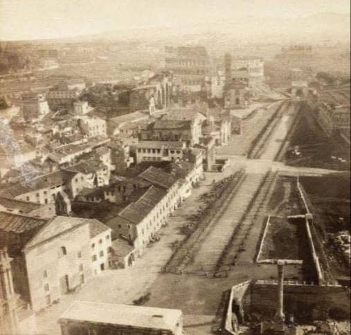 Сепия: городская застройка и широкая дорога, уходящая к Колизею на горизонте; на переднем плане колонна и участки раскопок.