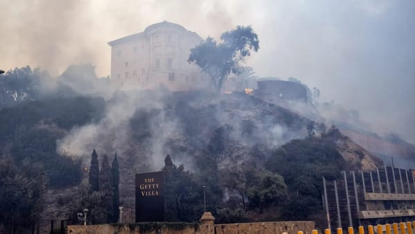 Дым над холмом с историческим зданием и табличкой «The Getty Villa», на склоне видны очаги огня.