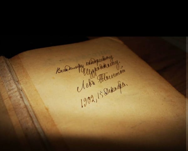 Раскрытая старая книга с рукописной надписью, подписью Лев Толстой и датой 15 декабря 1902 года на первой странице.