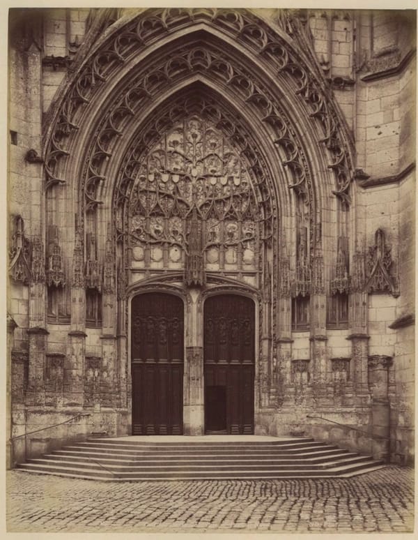 Старая коричневатая фотография готического портала с двустворчатой дверью, резным орнаментом и ступенями перед входом.