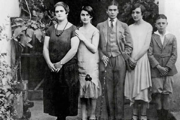 На чёрно-белом снимке в ряд стоят пятеро, в центре человек в костюме с галстуком и тростью, рядом три женщины и мальчик.