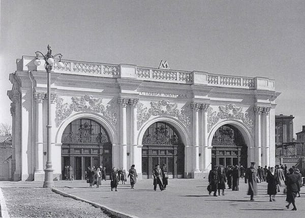 Белый павильон станции Арбатская московского метро с тремя арочными входами и лепным декором, перед ним прохожие, снимок 1953 года.