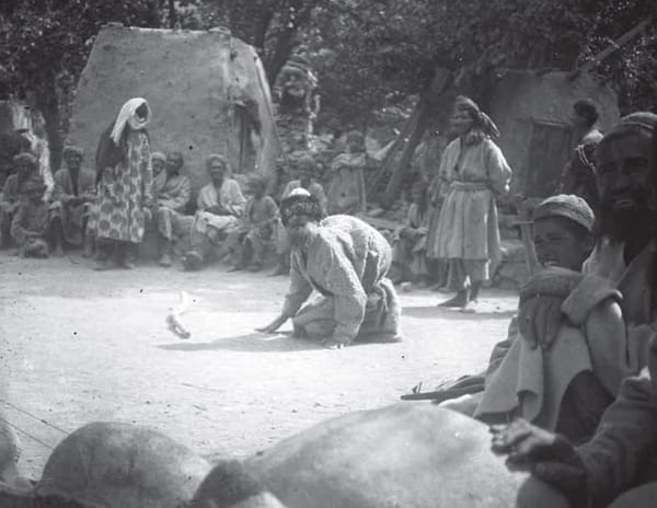 Танцующие мужчины в кишлаке Басид, в том числе один из них, переодетый в женщину, окруженный толпой зрителей